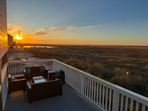 a sunset on a deck with chairs and tables at Beach House with Breathtaking Sunsets - Perfect for Couples and Families! in Bolivar Peninsula