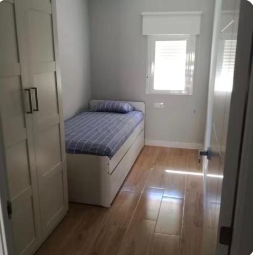 a small bedroom with a bed and a window at Bonito piso in Puerto Real