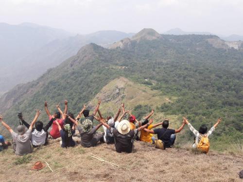 a group of people sitting on top of a mountain at Fogveilhomestay in Idukki