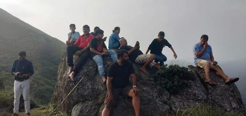 a group of people sitting on top of a mountain at Fogveilhomestay in Idukki