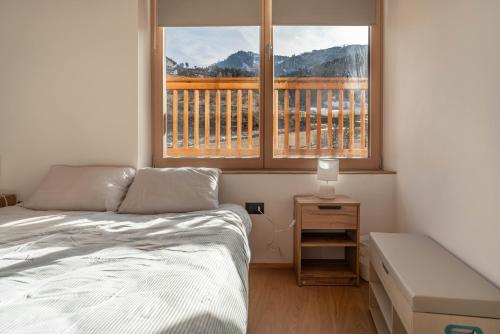 a bedroom with a bed and two windows with a balcony at Duplex Cermis in Cavalese