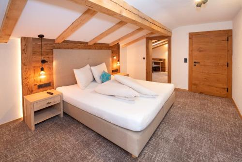 a bedroom with a large white bed and a wooden ceiling at Der Berghof in Alpbach
