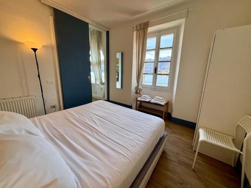 a bedroom with a large white bed and a window at -Ortaflats- Appartamento Gli Archi in Orta San Giulio