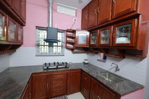 a kitchen with wooden cabinets and a sink at Greenhaven Homestay Villa in Ettumānūr