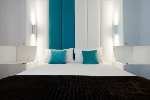 a bedroom with a large white bed with blue pillows at Hotel Ecu in Genk