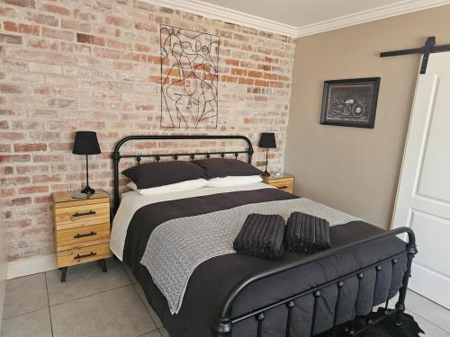 a bedroom with a bed and a brick wall at Cape Town Glam in Welgemoed
