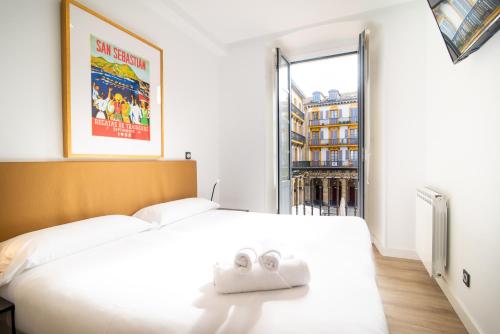 a bedroom with a white bed with two towels on it at Central Roomss in San Sebastián