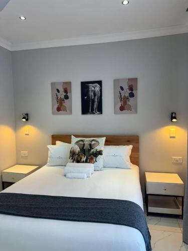 a bedroom with a large white bed with pictures on the wall at Elephant's Crest Lodge in Victoria Falls