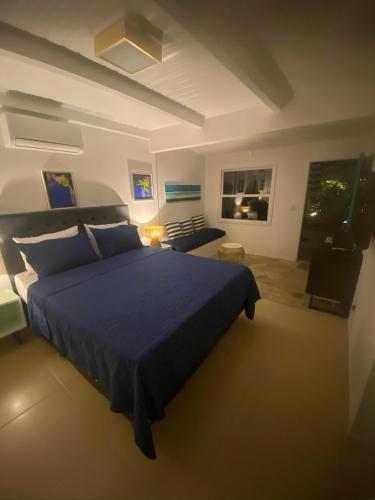 a bedroom with a blue bed and a living room at Casa Mediterrânea Geribá in Búzios