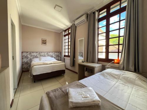 a hotel room with two beds and a window at Hotel Villa Souza Ltda in Santa Cruz do Sul