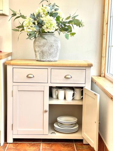 a white cabinet with a vase with flowers in it at The Lodge in Kelso