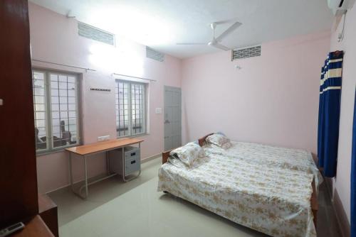 a bedroom with a bed and a desk in it at Greenhaven Homestay Villa in Ettumānūr