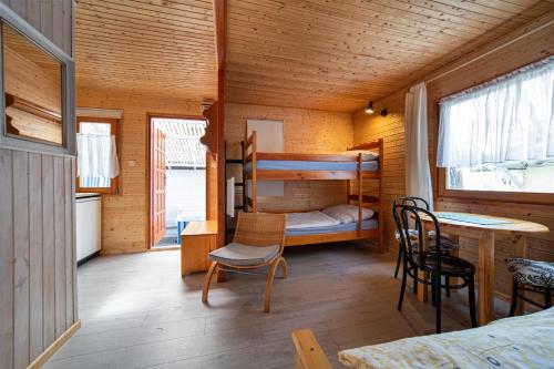 a room with a bunk bed and a desk and chairs at Proxial - domki letniskowe in Międzywodzie