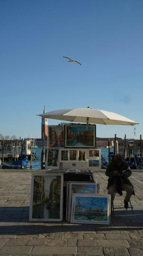 a woman is sitting in front of an umbrella at Gabrielli Luxury Apartments Venezia - Starhotels Collezione in Venice