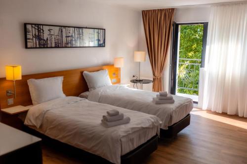 two beds in a hotel room with towels on them at CHR Vista in Nicoreşti