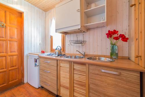 a kitchen with two sinks and a vase of red flowers at Proxial - domki letniskowe in Międzywodzie