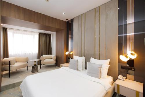 a hotel room with a large white bed and chairs at Hotel Terra Balneo in Galaţi