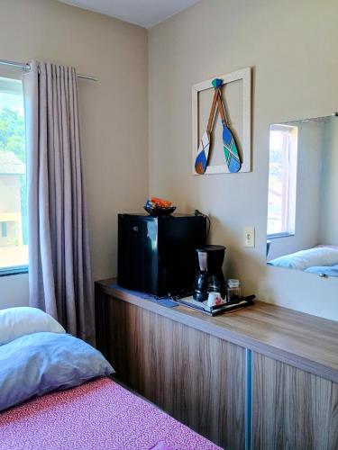 a bedroom with a wooden counter with a tv on it at Quarto em residência familiar in Navegantes