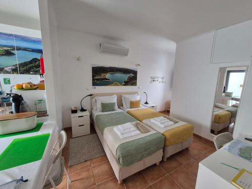 a small bedroom with two beds and a kitchen at Caminhos nos Levam pela Ilha in Ponta Delgada