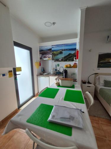 a kitchen with a table with green mats on it at Caminhos nos Levam pela Ilha in Ponta Delgada