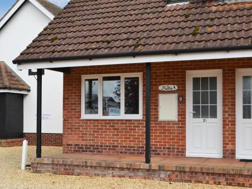 a red brick house with a white door at Puffin Cottage in Wroxham