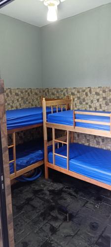 a room with three bunk beds with blue sheets at Casa para agrishow in Ribeirão Preto