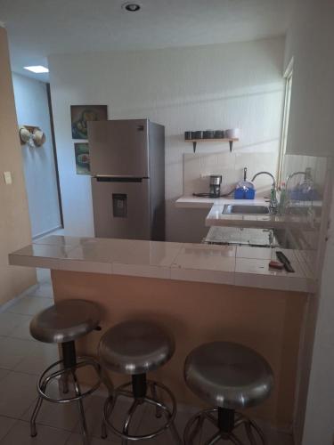 a kitchen with three bar stools and a refrigerator at Comfortable and nice house in Caucel in Mérida