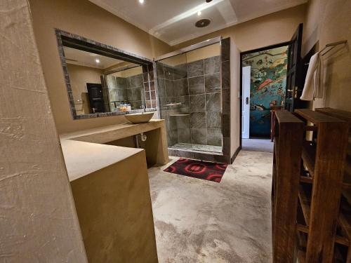 a bathroom with a shower and a sink and a mirror at MALI Boutique Lodge & Tube 'n Axe Budget Accommodation in Stormsrivier