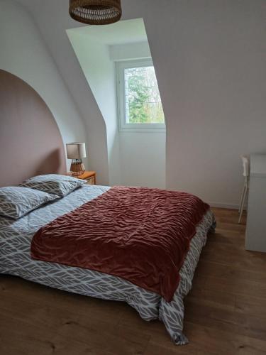 a bedroom with a bed with a red blanket on it at Proche parc 3 curés in Coatéval