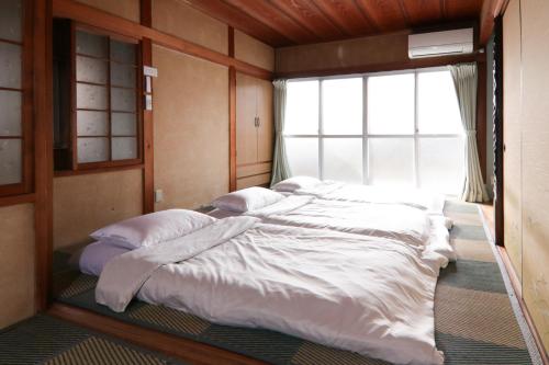 a large bed in a room with a window at 南栄駅1分 3寝室 最大9名 キッチン付一棟貸し パーキング1分 Showa Retro Japanese House 1min Station Entire Home for 9 in Toyohashi