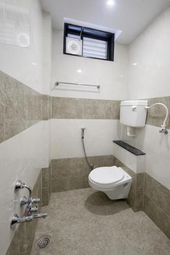 a bathroom with a toilet and a window at StayGuru Hari Om Residency in Bhuj