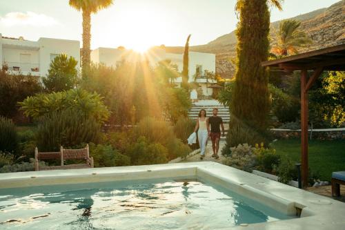 Ein Paar spaziert durch einen Garten mit Swimmingpool in der Unterkunft Caesars Gardens Hotel & Spa - Adults Only in Lindos