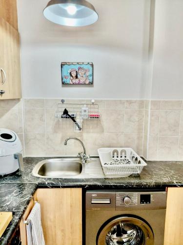 a kitchen with a sink and a washing machine at The Tipsy Expat - Paarl - Self Catering Apartment in Paarl