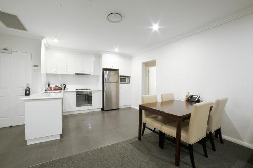 a kitchen and dining room with a table and chairs at Best Western Plus Bolton on the Park in Wagga Wagga