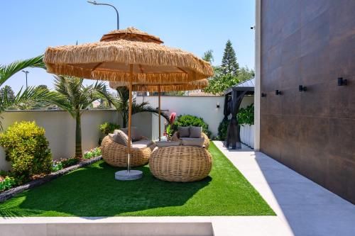 a patio with two chairs and an umbrella at אחוזת דוד - וילה יוקרתית עם בריכה פרטית מחוממת ומקורה in Hatzor haglilit