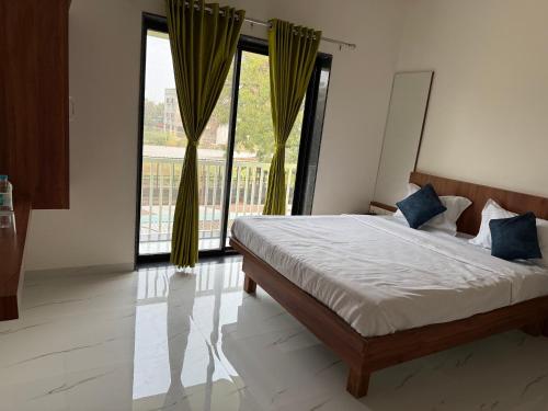 a bedroom with a bed and a large window at Aanandi Resort in Shirdi