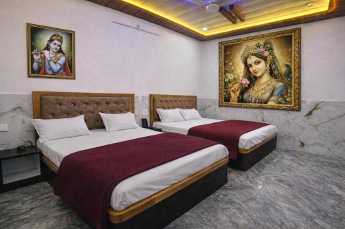 two beds in a room with a painting on the wall at Hotel Bhavishyaa Vrindavan in Vrindāvan