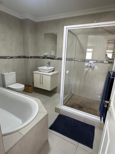 a bathroom with a tub and a shower and a sink at White Wicker House in Langebaan