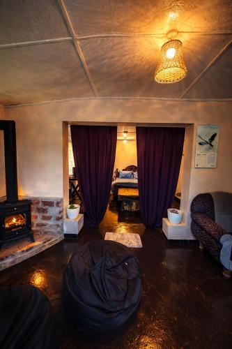 a living room with a fireplace and purple curtains at Blackpool Farm House in Nuwara Eliya