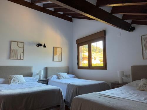 a room with three beds and a window at Apartamentos Rurales Valverde in Potes