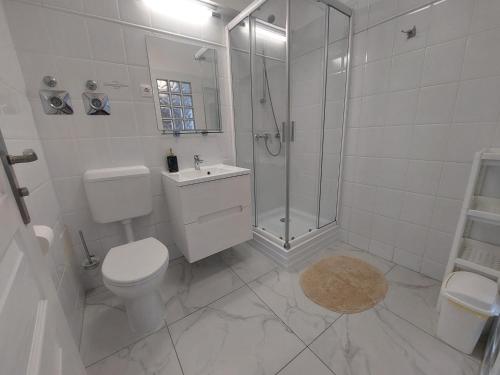 a white bathroom with a toilet and a shower at Holiday Art Garden&Spa in Balatonfüred
