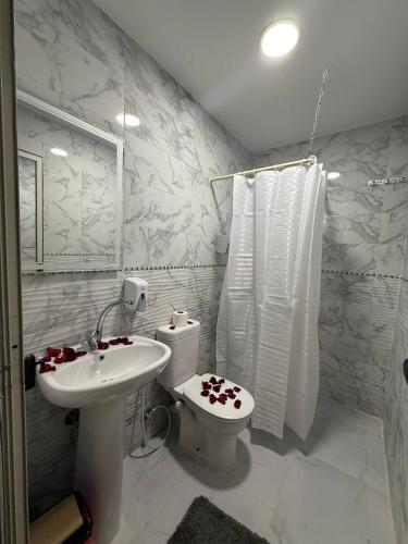 a white bathroom with a toilet and a sink at Golden Palace Suites in Cairo
