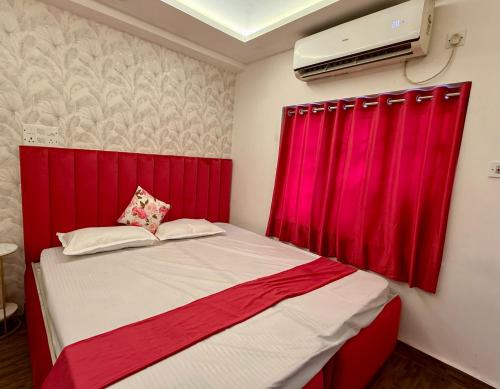 a bedroom with a red headboard and a red curtain at Cutesy space in Kolkata