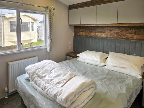 a bedroom with a bed with white sheets and a window at Beachside Holiday Park in Brean