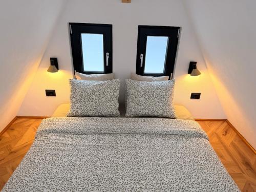 a bedroom with a bed with two windows at MooN by Sun&Moon Cabins in Măneciu