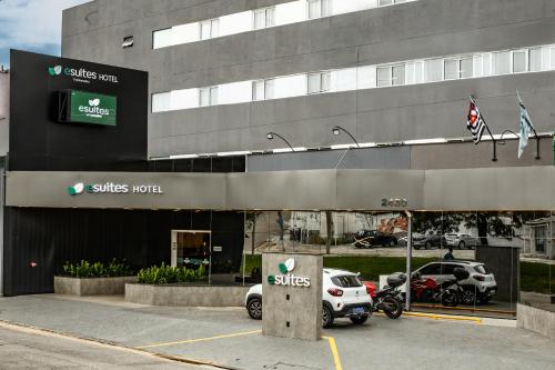 a hotel with cars parked in front of a building at Esuites Sorocaba in Sorocaba