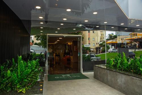 an open glass door of a building with plants at Esuites Sorocaba in Sorocaba