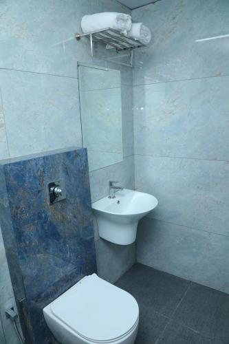 a bathroom with a white toilet and a sink at Hotel Prowell Apex - Kondapur in Hyderabad