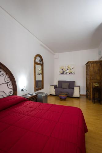 a bedroom with a red bed and a couch at B&B Il Sedile in Lecce