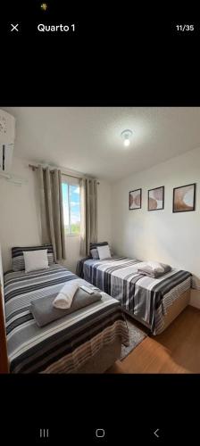 two beds sitting in a room with a window at Apartamento Próximo Arena pantanal in Cuiabá